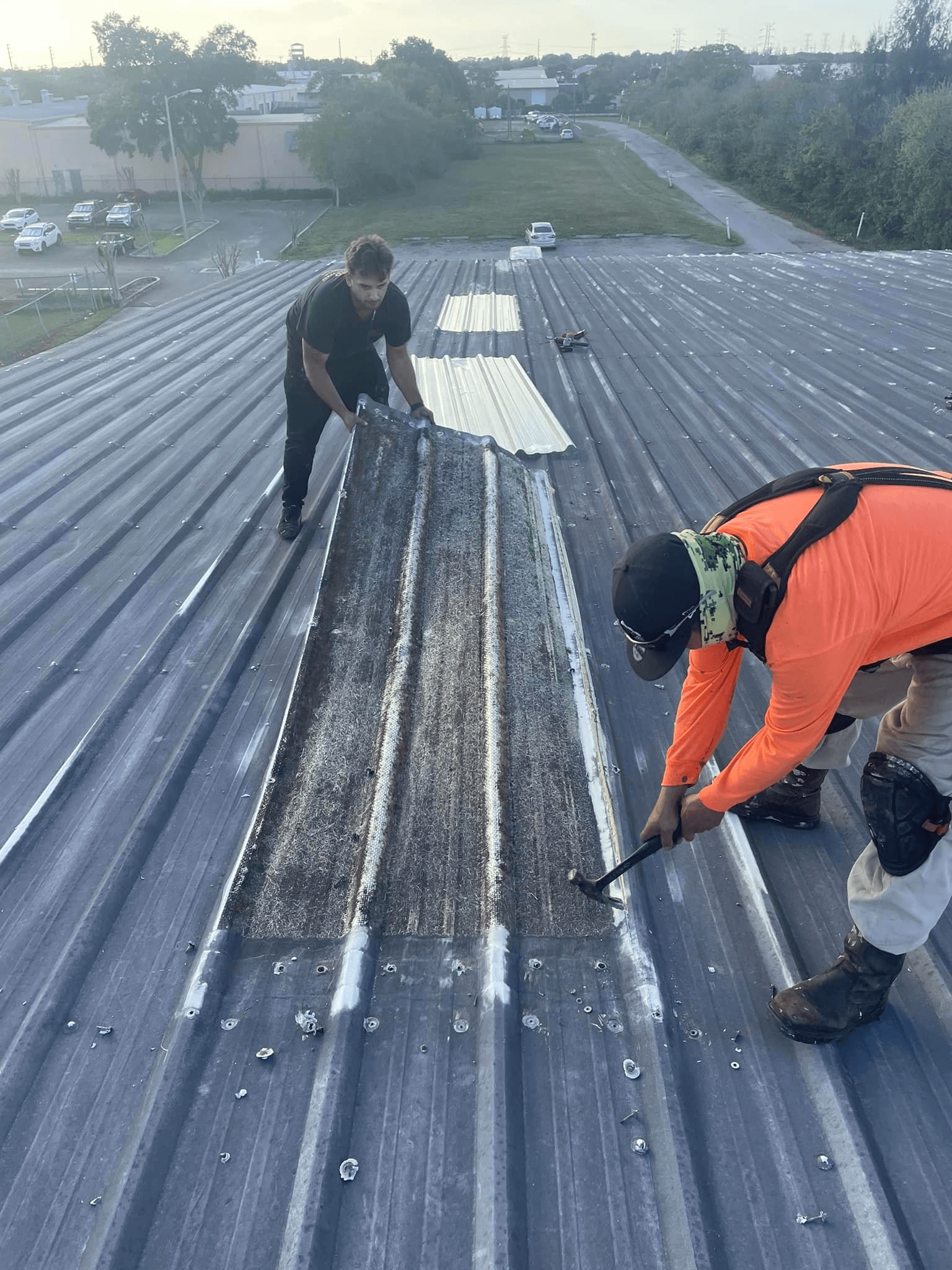 Roofing professional applying a patch repair on a commercial roof to prevent further damage.