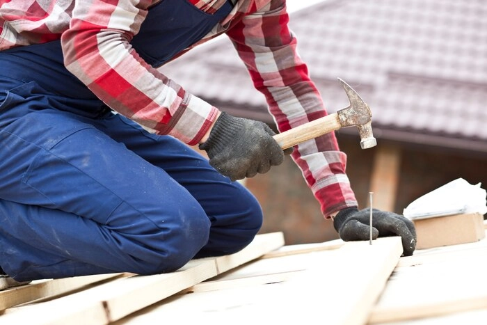 A man hammering a nail on a roof