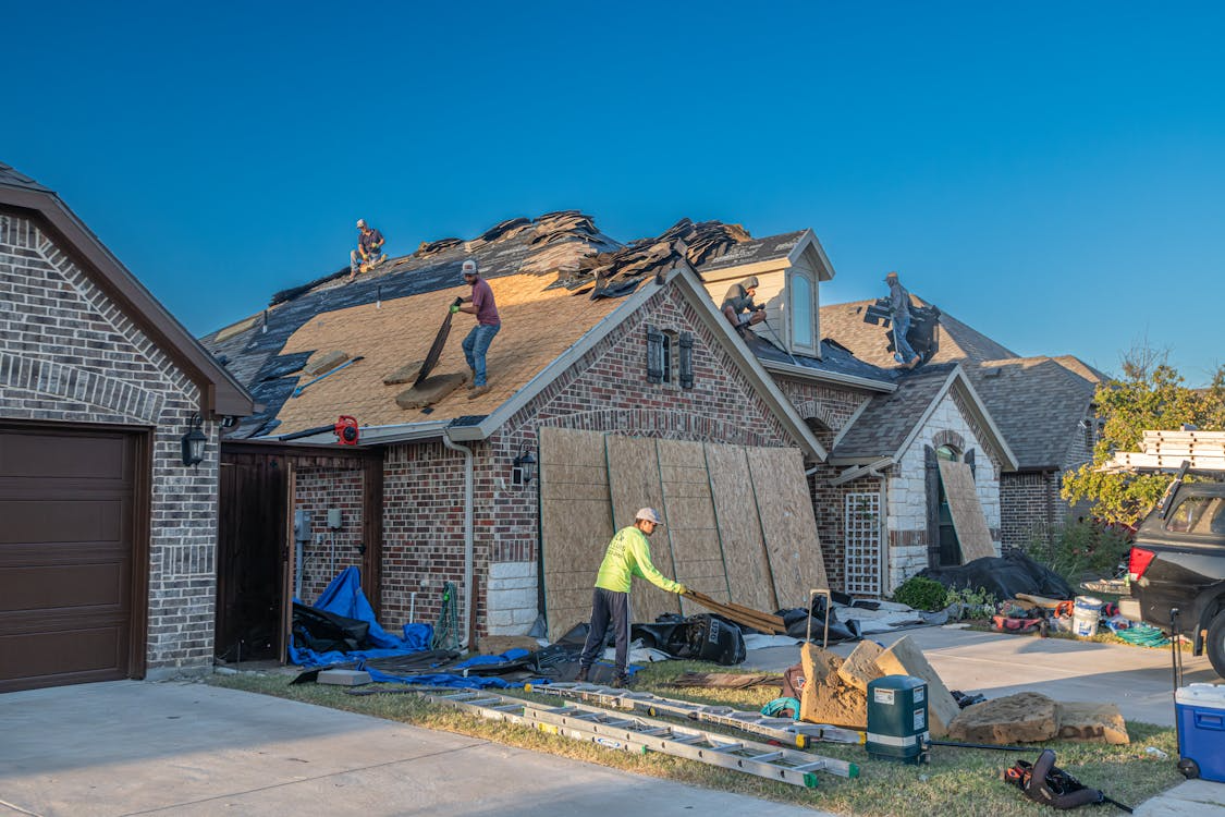 roofing crew applying protective tarp to a damaged residential roof