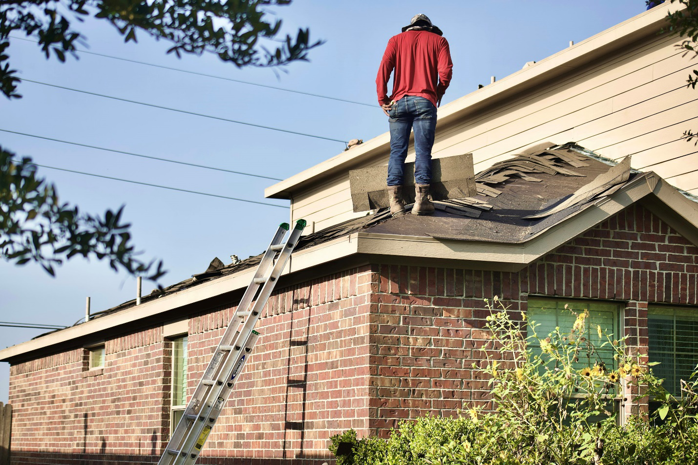 Roofer inspecting damaged roofing for repairs