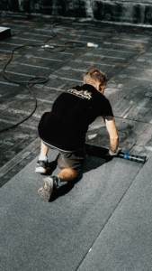 a construction worker applying roofing material for durability on top of a roof