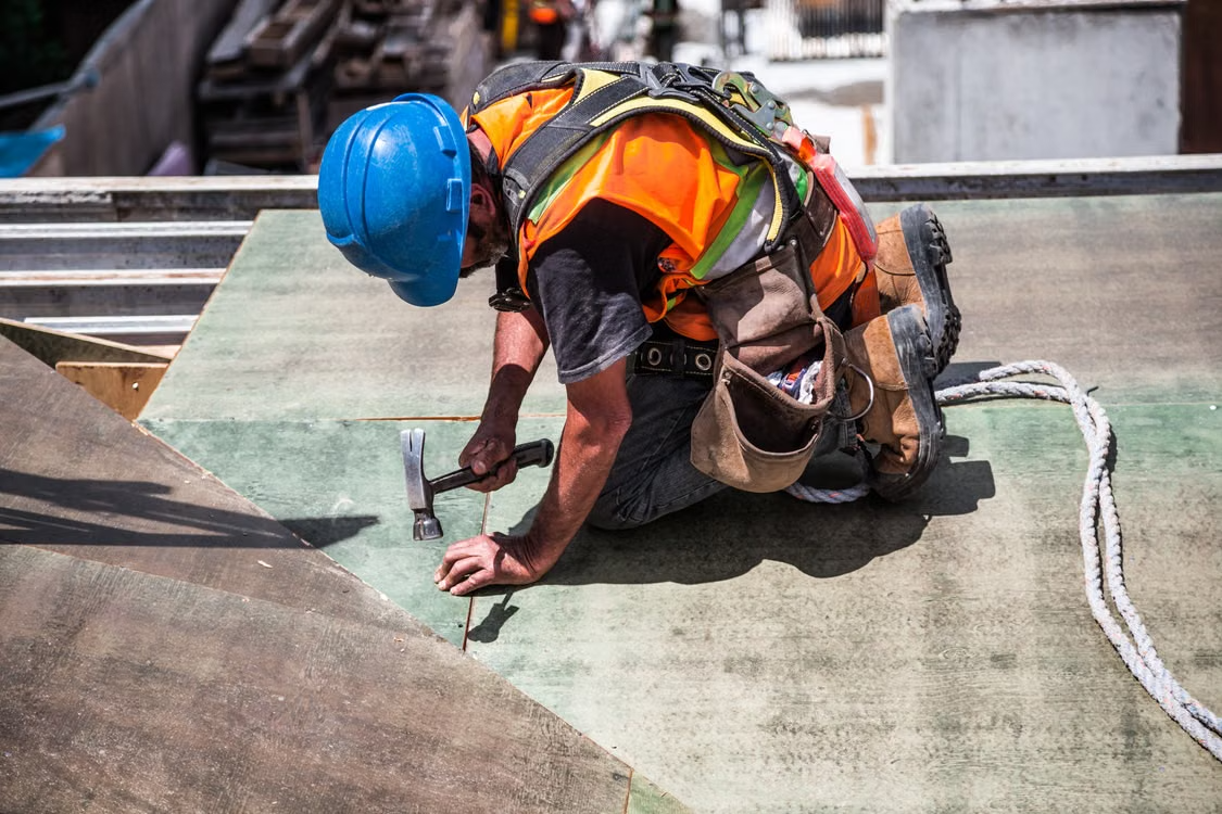 a man wearing a blue helmet working on top of a roof using a hammer