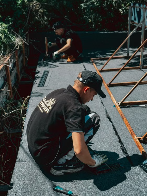 a worker applying a waterproof membrane on a roof