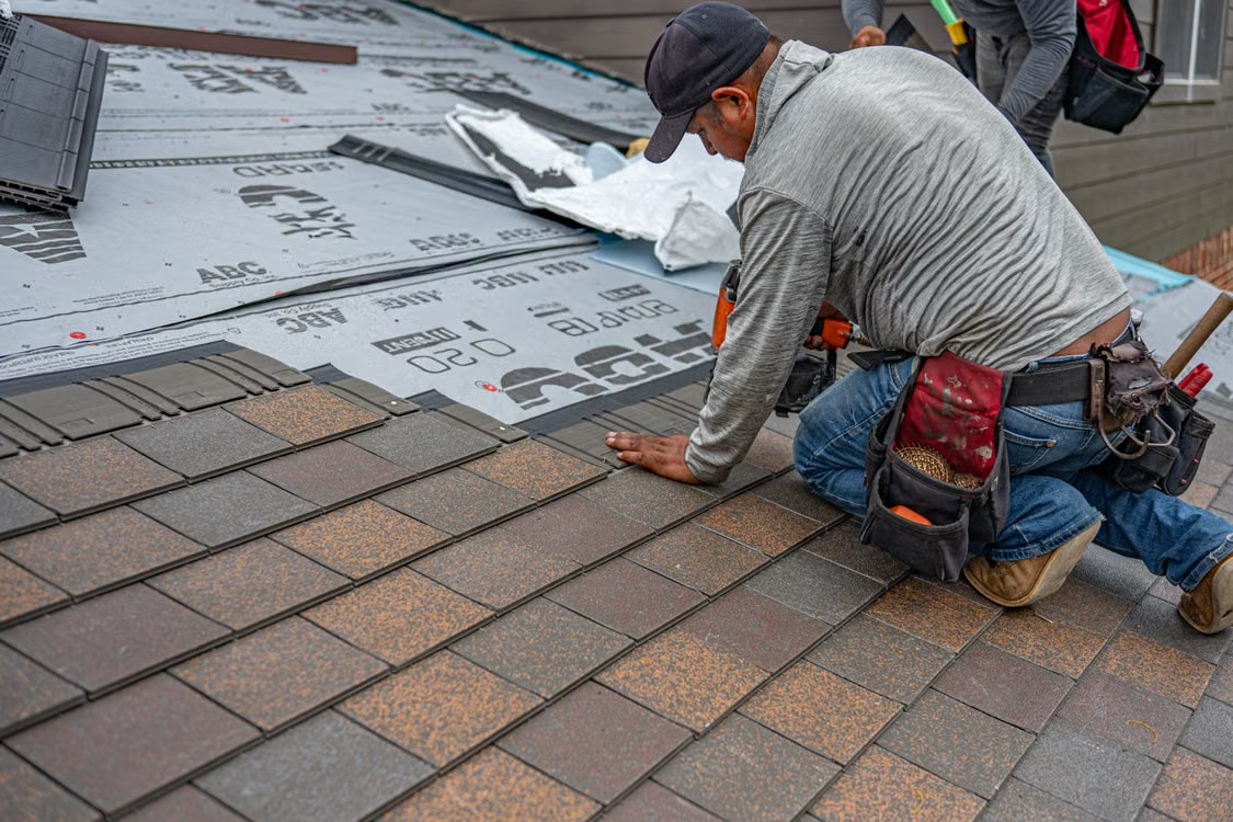 close-up of a worker replacing roof tiles on a roof