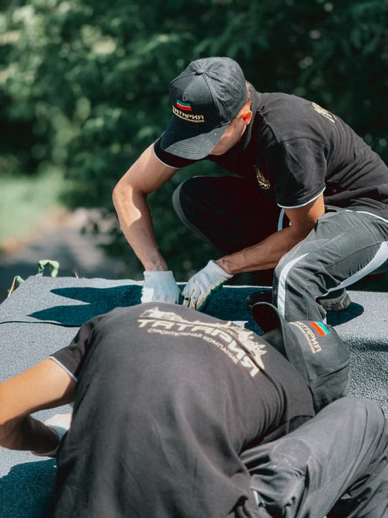 workers applying roofing material on a rooftop