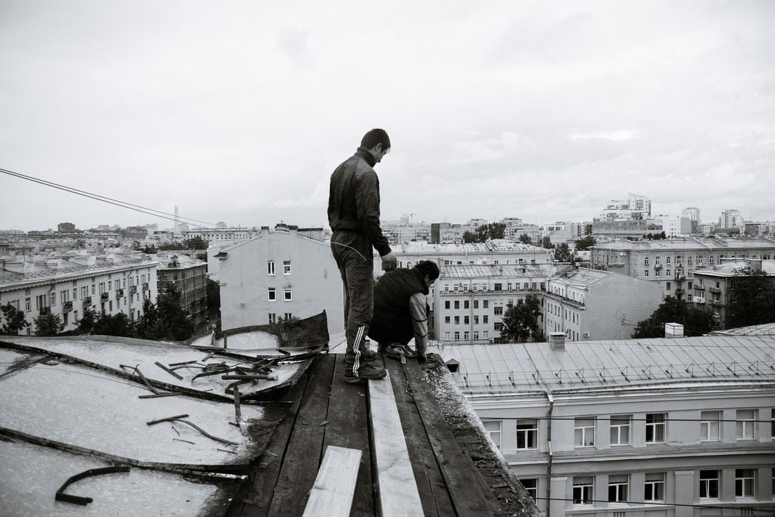 two men working on fixing a damaged roof