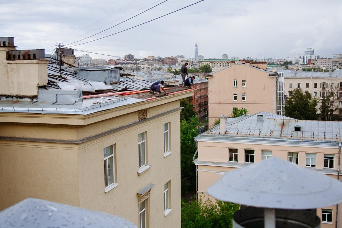 men working on roof inspection at the top of a building
